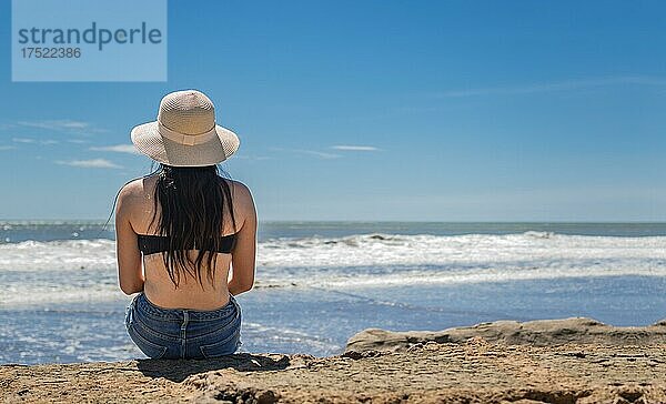 Frau mit Hut vom Rücken zum Meer  Mädchen mit Hut schaut zum Meer  Urlaubskonzept  Rückansicht eines Mädchens  das das Meer beobachtet