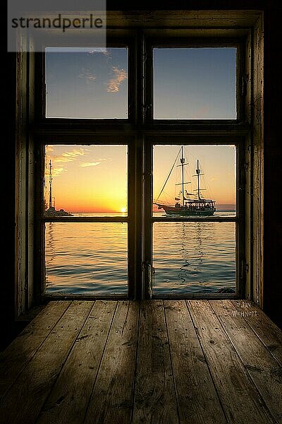 Toller blick aus einem Holzfenster mit Holztisch  auf einen see mit Segelboot. Das boot fährt in den Sonnenuntergang. Siofik  Balaton  Plattensee  Ungarn  Europa