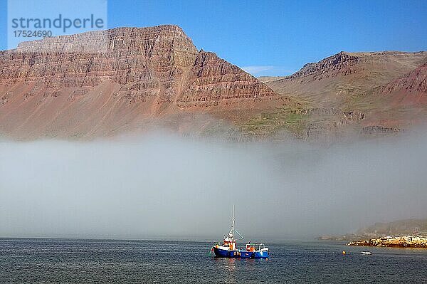 Nebelwand  rotes Vulkangestein und ein kleines Fischereifahrzeug  Diskoinsel  Diskobucht  Qeqertarsuaq  Arktis  Grönland  Arktis  Dänemark  Nordamerika