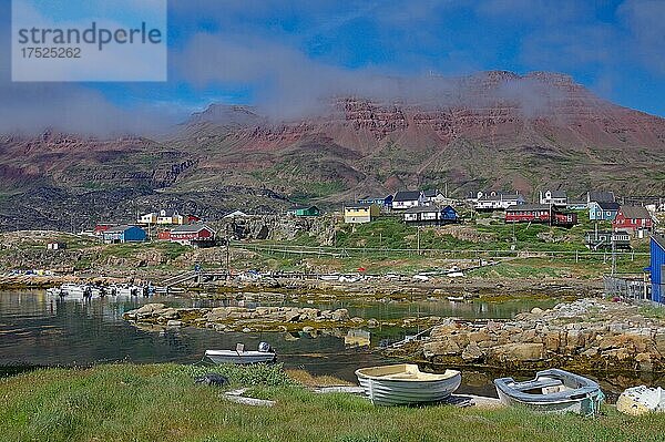 Kleine Boote liegen vor Häusern und roten  vulkanisch geprägten Bergen  auflösender Nebel  Qeqertarsuaq  Diskoinsel  Qeqertarsuaq  Arktis  Grönland  Dänemark  Nordamerika