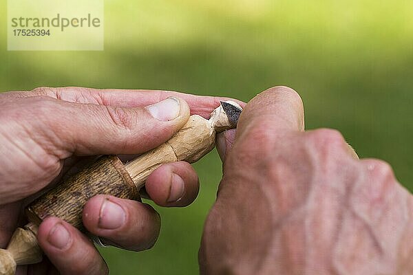 Mann schnitzt an einer kleinen Holzfigur  Detailaufnahme mit Händen  Holz und Schnitzmesser. Värmland  Schweden  Europa