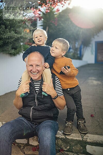 Vater mit seinen beiden Söhnen  die sich während des Herbstes im Freien umarmen