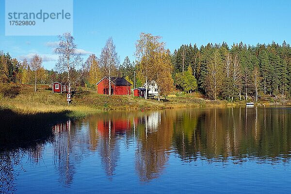 Kleines rotes Haus spiegelt sich im ruhigen Wasser eines Sees  Herbstlicht  Bullaren  Bohuslän  Schweden  Europa