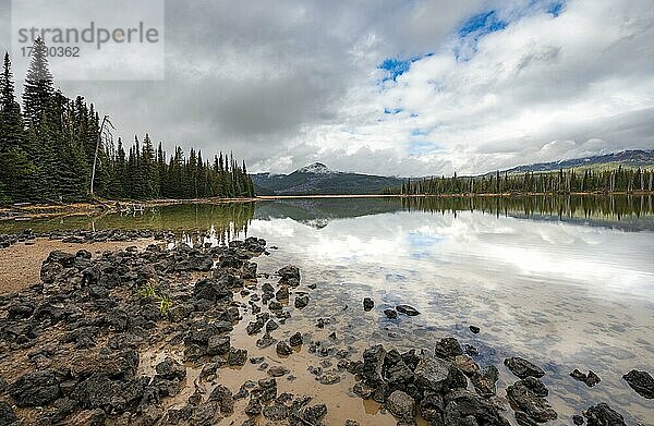 Schwarze Steine am Seeufer  Landschaft mit Wald spiegelt sich im See  Sparks Lake  Oregon  USA  Nordamerika