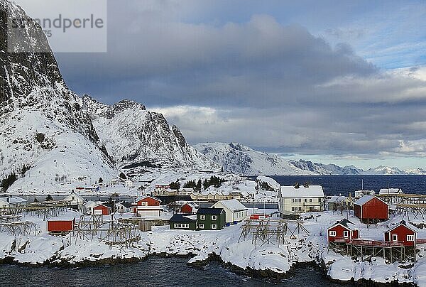 Winterliche  nordische Landschaft mit roten Häusern  Rorbuer  Meer  Berge  Schnee  Hamnøy  Nordland  Lofoten  Norwegen  Europa
