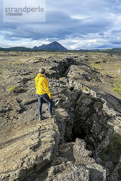 Frau steht an Kontinentalspalte zwischen Nordamerikanischer und Eurasischer Platte  Mittelatlantischer Rücken  Grabenbruch  Silfra-Spalte  Krafla  Nordisland  Island  Europa