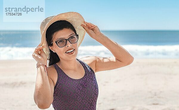 Frau mit Hut glücklich am Strand  Strandurlaub Konzept