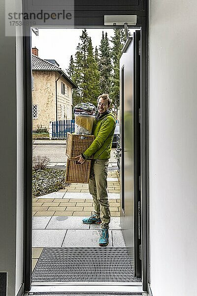 Junger Mann trägt schwere Umzugskisten  Blick durch Eingangstüre  Umzug in eine Neue Wohnung  München  Bayern  Deutschland  Europa