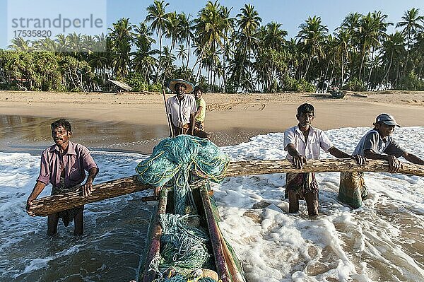 Fischer bei der Arbeit  Fischer schieben Fischerboot vom Sandstrand ins Meer  Einbaum mit Ausleger  Darwins Beach  Wella Odaya bei Ranna  Südprovinz  Sri Lanka  Indischer Ozean  Asien