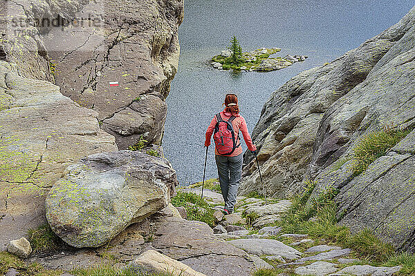 Frau mit Rucksack und Wanderstöcken auf dem Weg zum See Lac Fourca  Seealpen  Nationalpark Mercantour  Frankreich