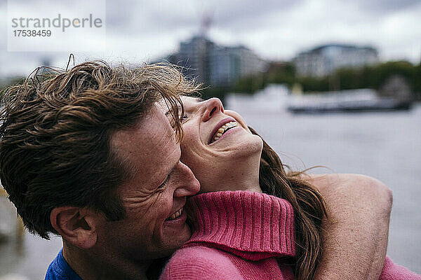 Man embracing cheerful woman from behind