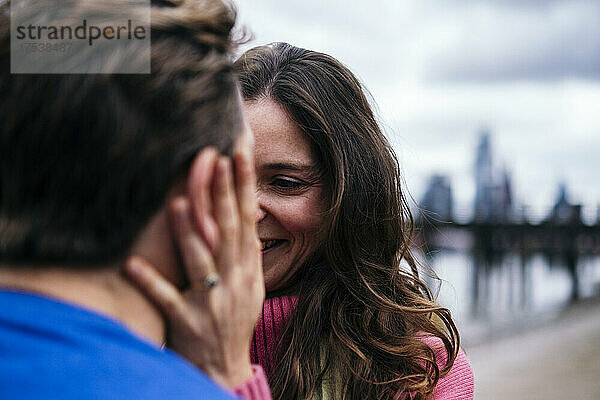 Smiling woman looking and touching man face