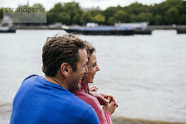 Happy man embracing woman at riverbank