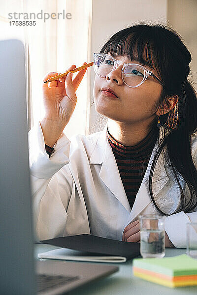 Junger Wissenschaftler mit Brille denkt im Labor nach