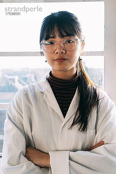 Confident scientist standing with arms crossed in laboratory