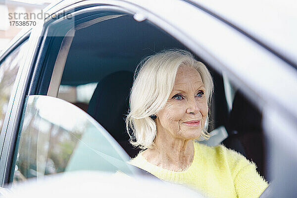Lächelnde ältere Frau mit weißem Haar  die Auto fährt