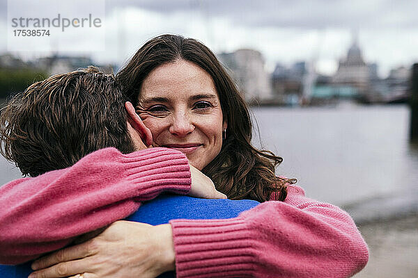Smiling woman embracing man at riverbank