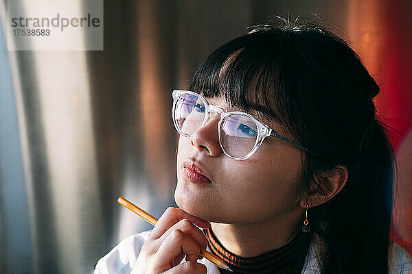 Young chemist wearing eyeglasses contemplating in laboratory