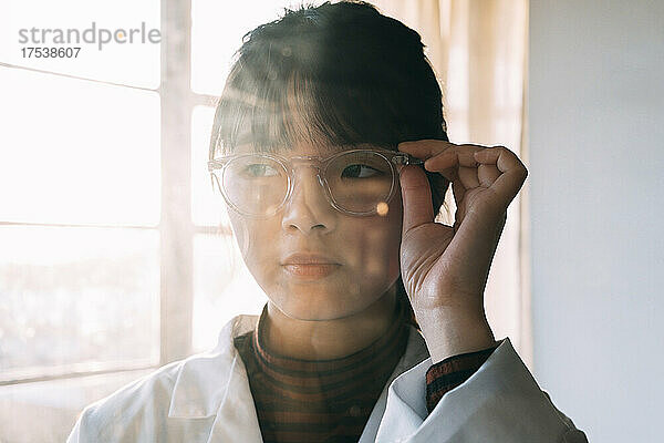 Young scientist wearing eyeglasses looking away in laboratory