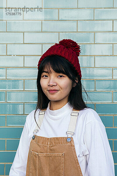 Smiling woman wearing knit hat in front of brick wall