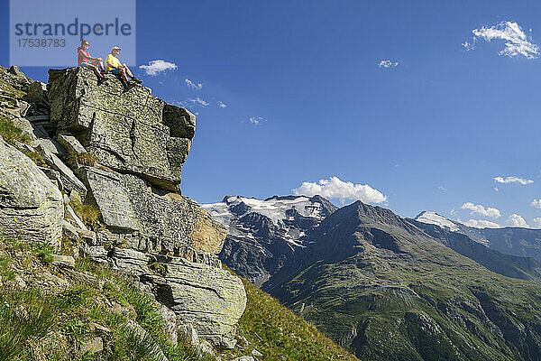 Wanderer sitzen am sonnigen Tag auf einer Klippe Vanoise-Massiv  Nationalpark Vanoise  Frankreich