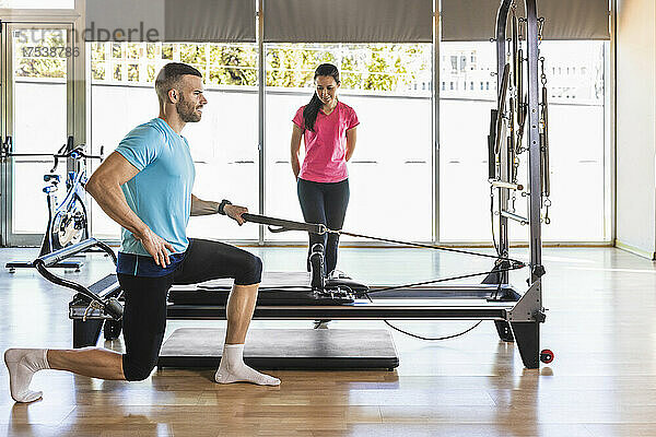 Fitness instructor guiding athlete to exercise with gym equipment