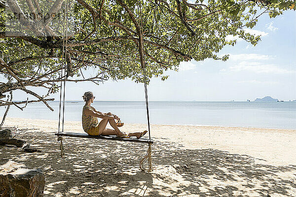 Woman sitting on swing at Ao Nang beach  Krabi Province  Thailand