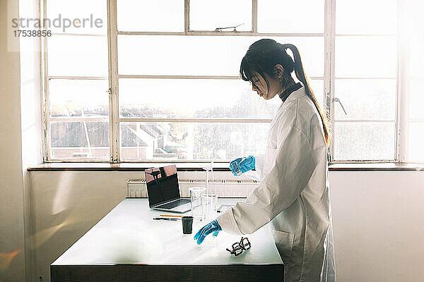 Young scientist working on table near window