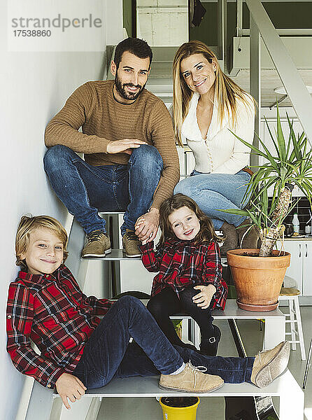 Smiling family sitting together on staircase at home