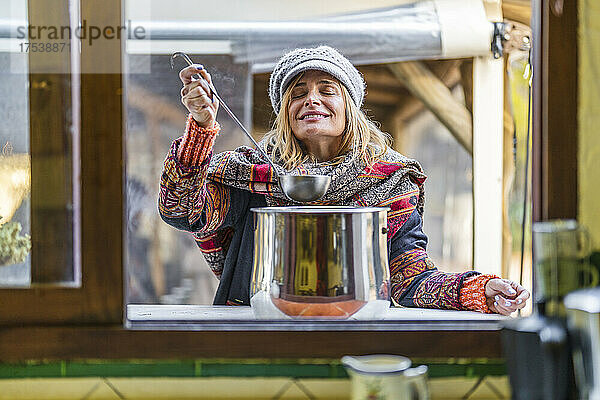 Smiling woman with eyes closed holding ladle