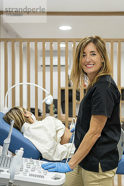 Lächelnder Gynäkologe führt Ultraschall an Patientin im Krankenhaus durch