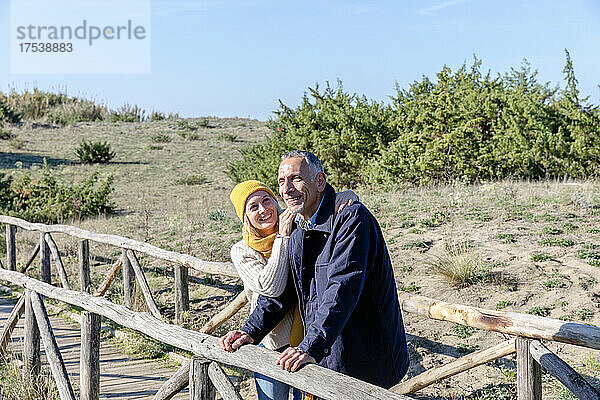 Lächelndes Paar steht zusammen auf einer Holzbrücke