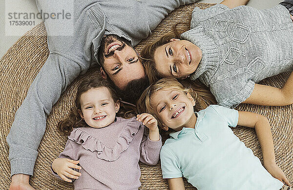 Happy family lying together on rug at home