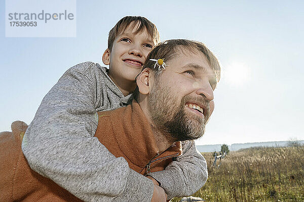 Father giving son piggyback ride on sunny day