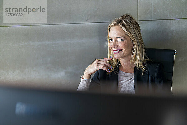 Beautiful businesswoman smiling in front of wall