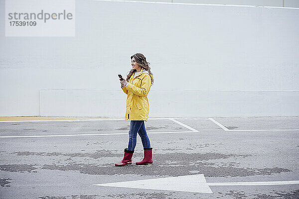 Junge Frau mit Smartphone läuft auf der Straße