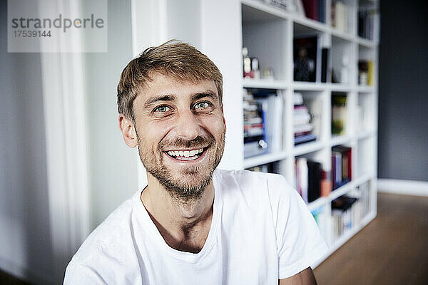 Smiling man in front of bookshelf at home