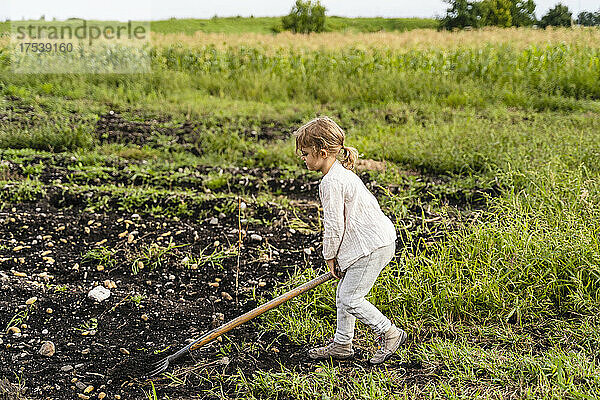 Girl using pitchfork in agricultural field