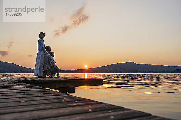 Family with daughter looking at sunset view from jetty  Mondsee  Austria