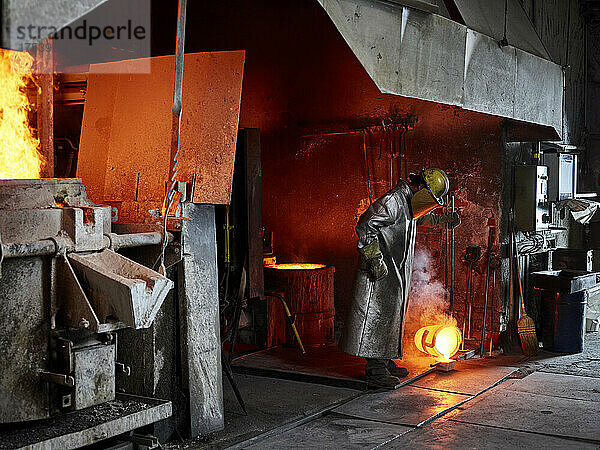 Handwerker gießt brennendes Metall  während er in der Industrie arbeitet