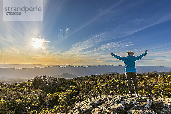 Australia  Victoria  Female tourist standing with raised arms on summit of Mount William at sunset