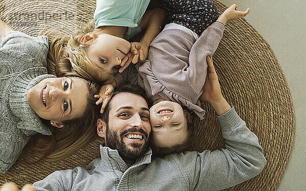 Happy parents with children lying on rug at home