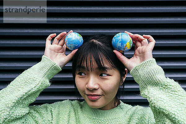 Woman holding toy globes over head