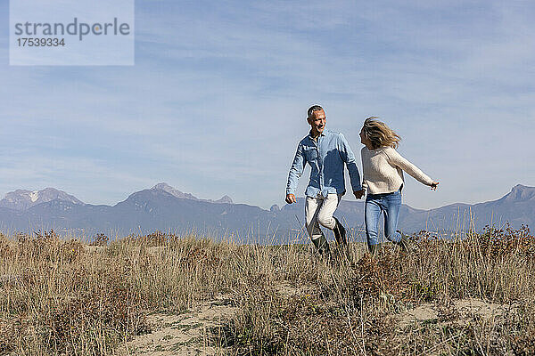Happy couple running together at dunes