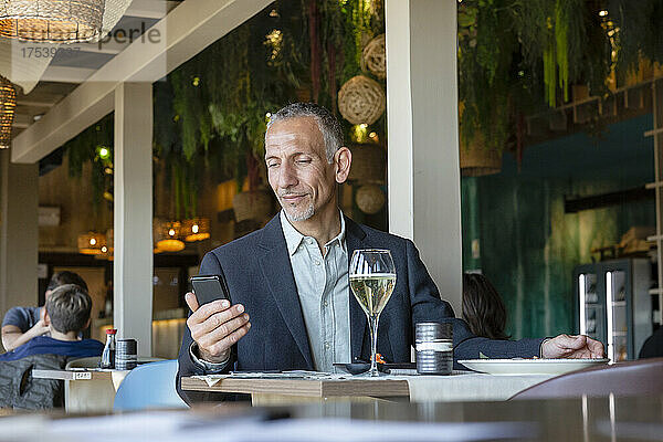 Geschäftsmann schaut im Restaurant auf sein Smartphone