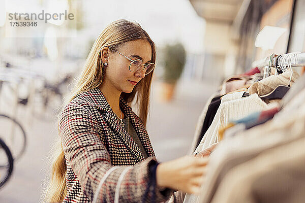 Junge Frau kauft Kleidung vor dem Laden