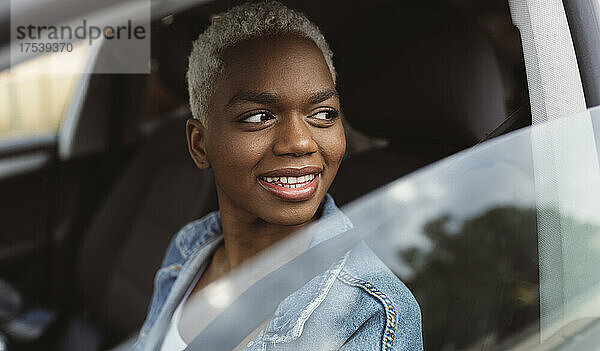 Smiling woman sitting in car looking out through window