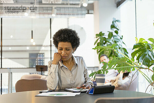 Geschäftsfrau prüft Dokument am Tisch im Büro