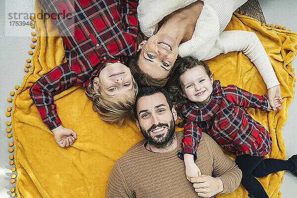 Lächelnde Eltern und Kinder  die zu Hause auf einer Decke liegen