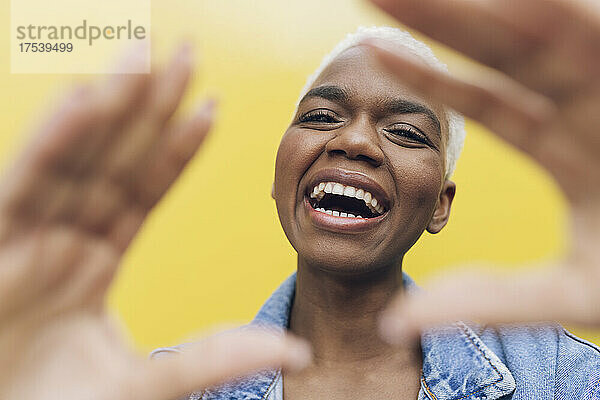 Laughing woman gesturing against yellow background